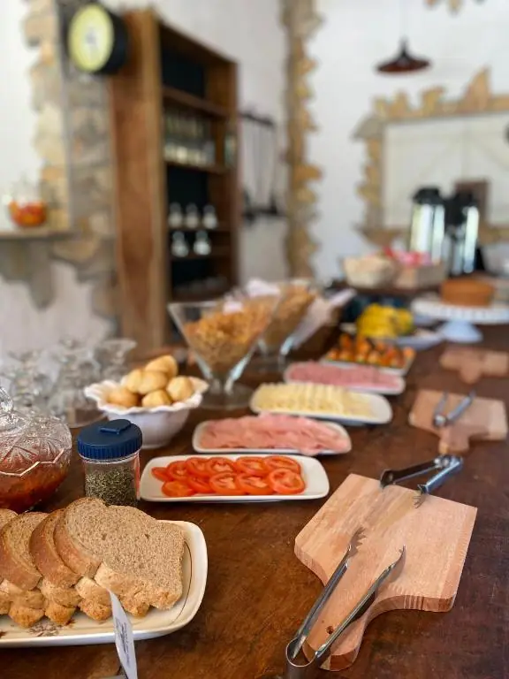 Pães, frios, tomate e geleia sobre a mesa de madeira