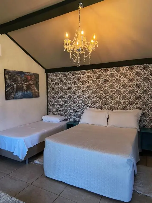 Quarto sob o telhado com lustre de cristal, cama de casal e cama de solteiro
