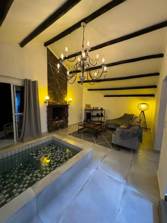 Sala com piscina interna, lareira de pedra e lustre aceso à noite